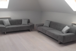 Kanapy w szarej tkaninie z ozdobnymi jaśkami…